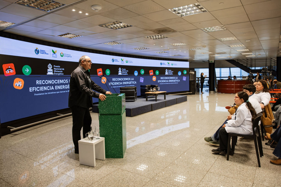 Christian Font habla en atril; se observa paneo general del espacio, escenario y pantalla.