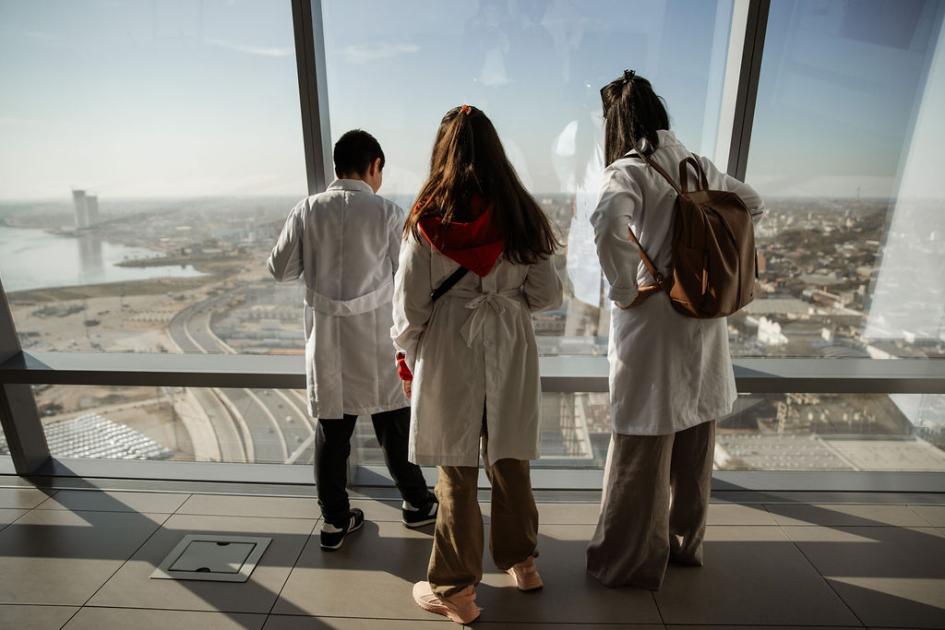 Estudiantes y docente de espalda mirando la vista panorámica del mirador, desde el piso 26