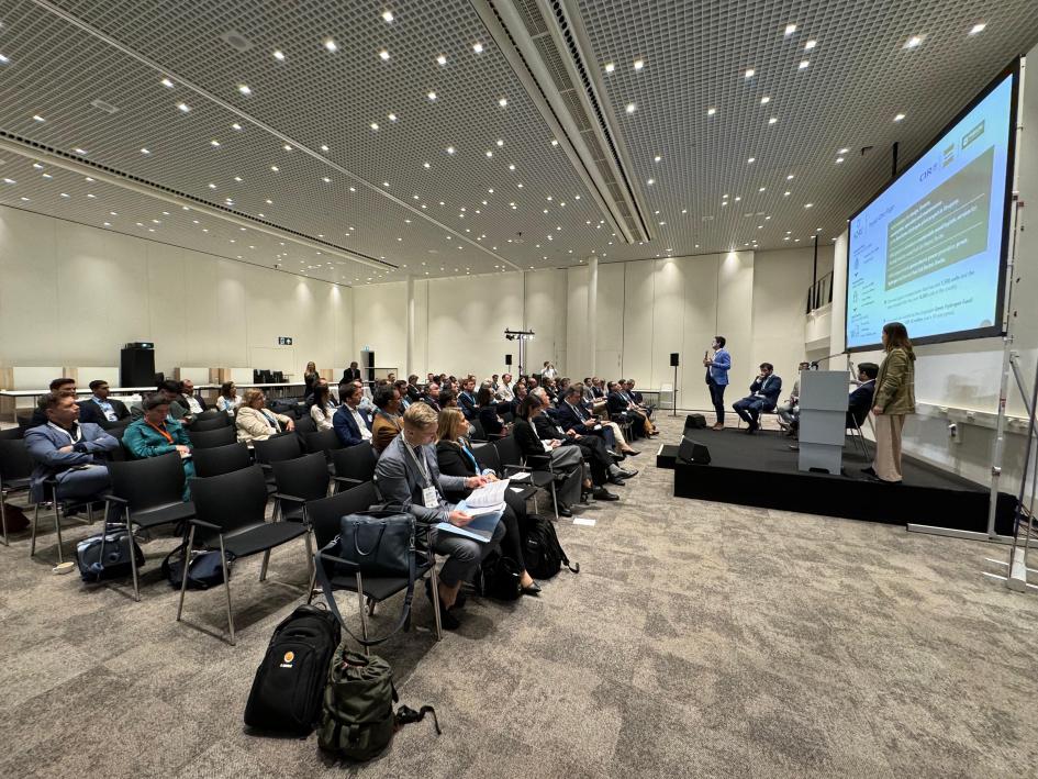 Público del side event dedicado a Uruguay Público a la izquierda; a la derecha, escenario con disertantes; arriba de ellos, pantalla