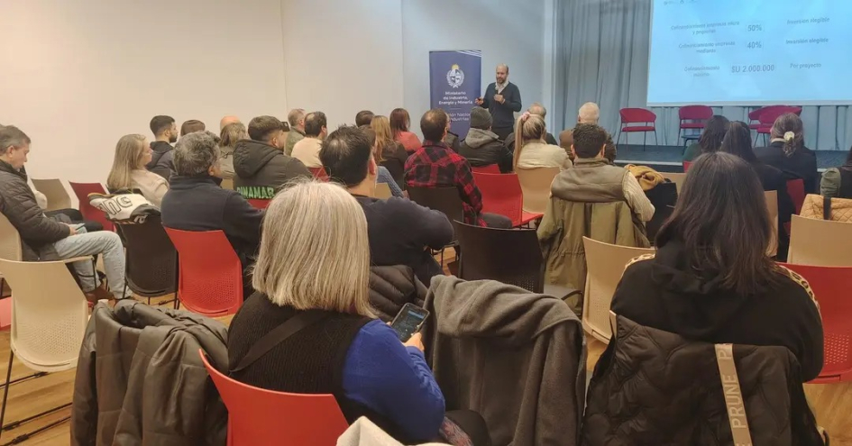 Ángel Larrama, en el taller de Pando Ángel Larrama, de pie; asistentes, sentados y setnadas, de espalda