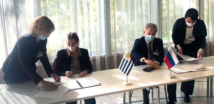 Uruguay y Rusia firmaron un memorándum de entendimiento Estrada y el representante de Rusia firman documentos en una larga mesa. A su lado hay dos personas.