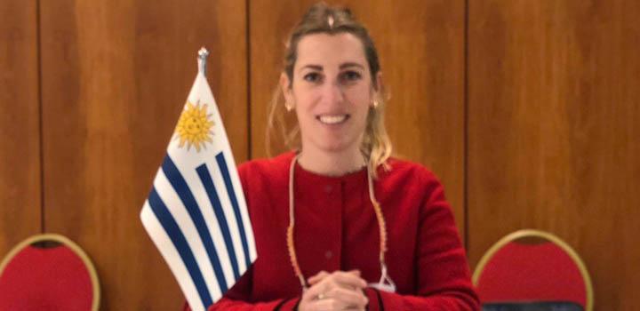 La directora Lucía Estrada, vestida de rojo, con una bandera de Uruguay a su lado