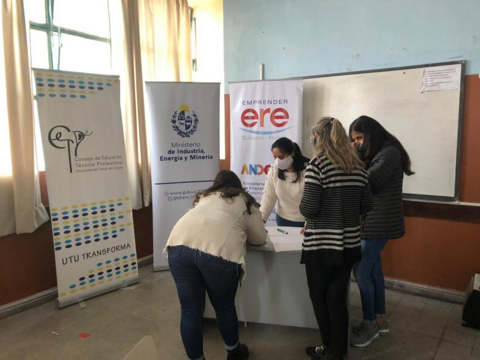 Taller 2: cuatro personas se unen frente a una mesa; detrás hay banners de instituciones