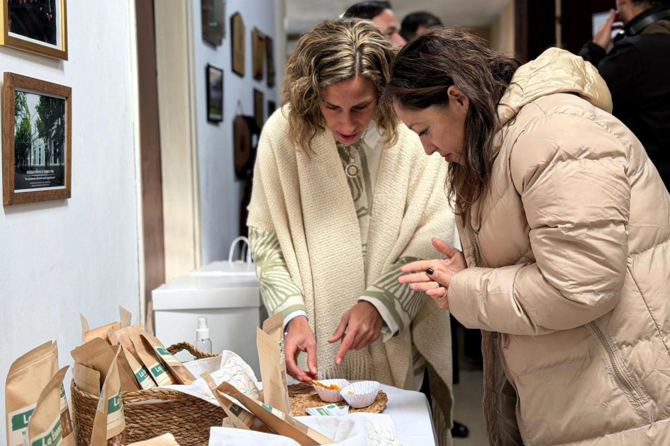 La ministra Fernanda Cardona conoció parte del trabajo de las y los productores locales Una mujer muestra a la ministra productos artesanales, ubicados sobre una mesa