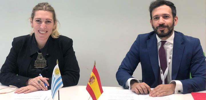 La directora Estrada junto al representante de España; se ven las banderas de ambos países