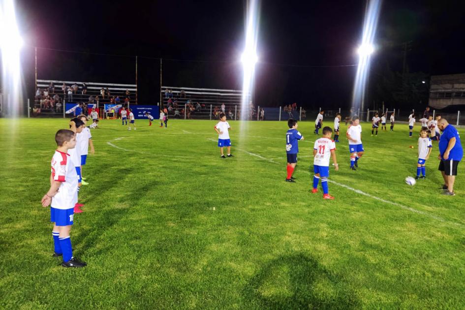 Nuevas luminarias en la cancha de fútbol infantil del Club Nacional de Fútbol de Nueva Helvecia Niños juegan al fútbol en la cancha, con los focos encendidos