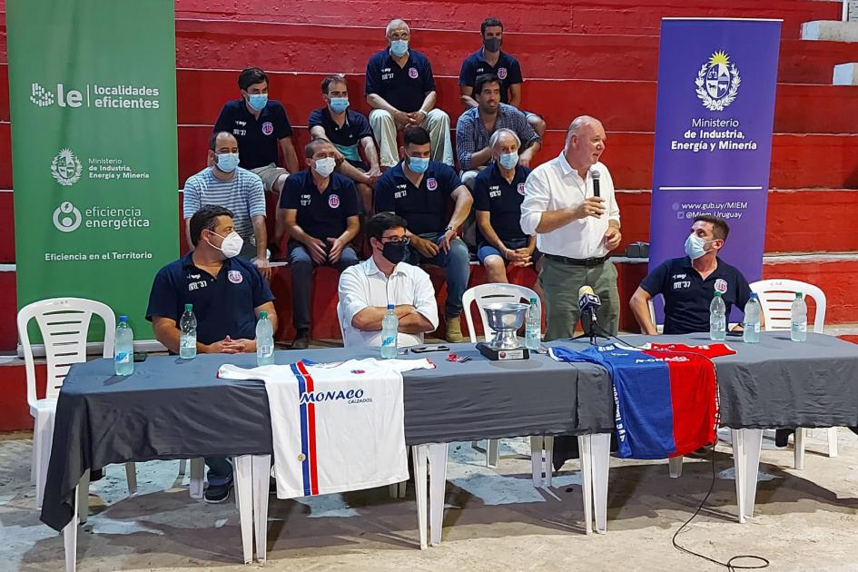 Ministro interino Walter Verri y autoridades durante la inauguración del proyecto del Club Estudiantes de Tacuarembó Ministro interino Verri habla de pie en la mesa de autoridades; detrás hay gente en la tribuna