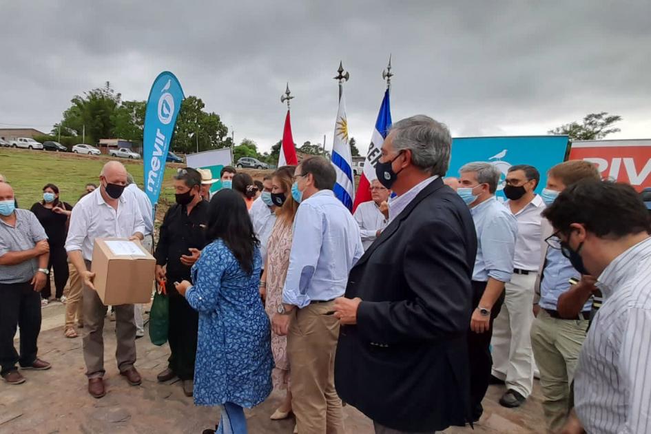 La inauguración se realizó en el barrio Tres Cruces de Rivera El ministro interino Verri, rodeado de personas, recibe una caja; detrás se ven pabellones y banners
