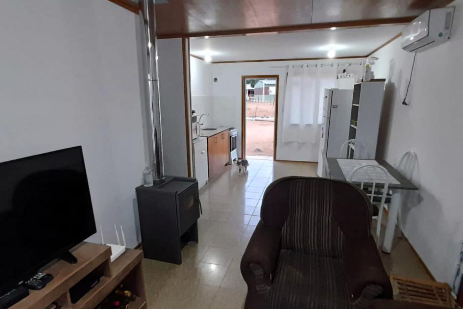 Interior de una vivienda; se ven muebles y un televisor; las paredes son blancas