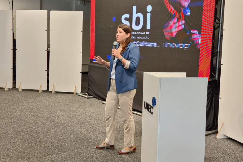 Coordinadora del proyecto, la funcionaria del MIEM Natalia Mamberto Una mujer joven habla al lado de un atril; detrás hay una pantalla