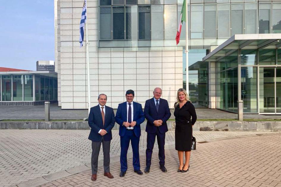Visita a Maire Tecnimont Verri, Cantero, Crego y otro hombre están frente a un edificio con banderas de Uruguay e Italia