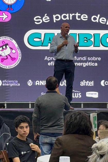 Subsecretario Walter Verri Verri habla; delante, público; detrás, pantalla que dice "Sé parte del cambio"