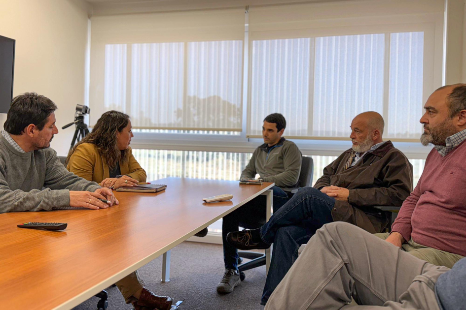 Visita a ADEMA Ministra sentada junto a un grupo de personas, alrededor de una mesa
