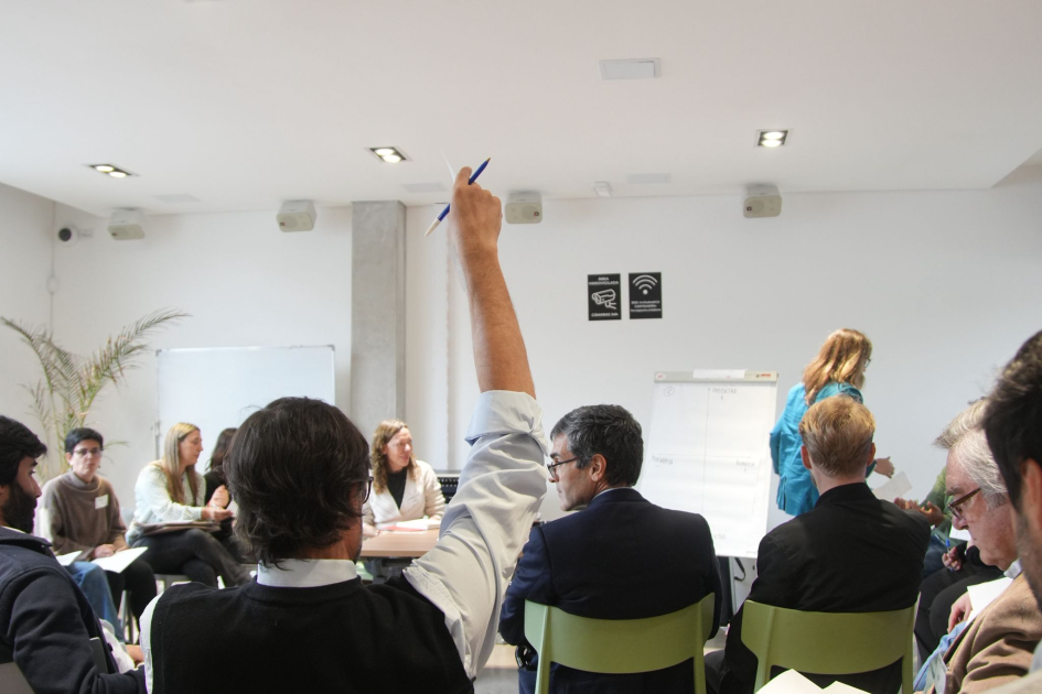 Actividad taller Grupo de personas sentadas. Un hombre levanta la mano.