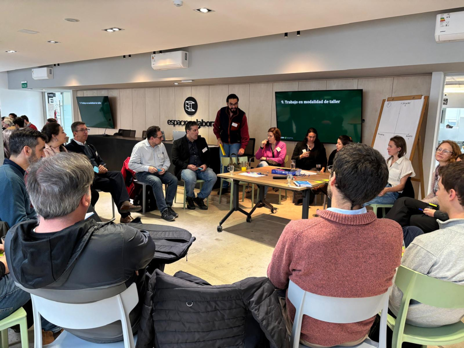 Actividad taller Gente sentada en ronda. Atrás se ve pantalla verde