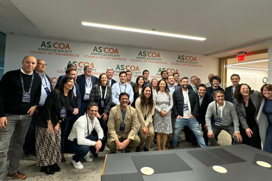 Visita a AS/COA Personas de pie y en cuclillas; detrás, banner de AS/COA