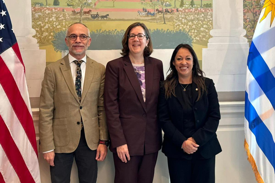 Reunión en Cámara de Comercio de Estados Unidos Cardona, un hombre y una mujer, junto a banderas de Uruguay y Estados Unidos