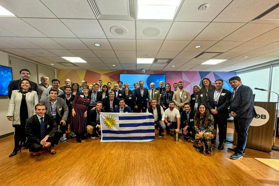 Reunión con BID Personas de pie y en cuclillas, con bandera de Uruguay