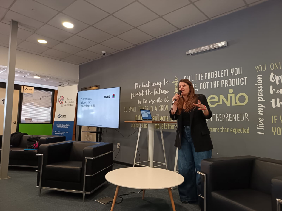 Lic. Ximena Camaño, de ANII. Foto: DNPI. Mujer, de pie, realiza una presentación