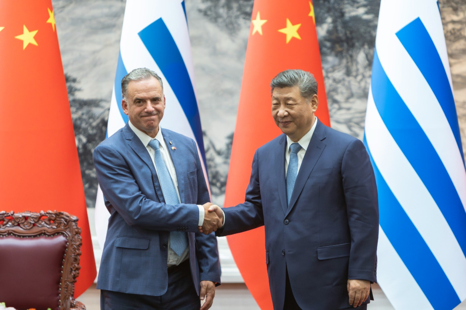 Yamandú Orsi y Xi Jinping se estrechan la mano. Detrás, banderas de China y Uruguay.