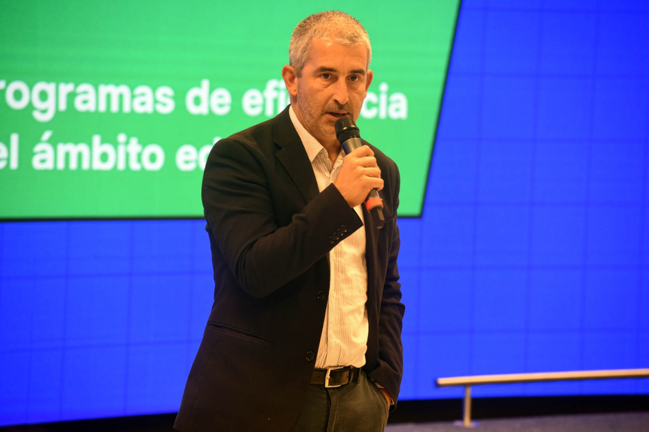 Pablo Caggiani habla a micrófono. Detrás, pantalla azul con recuadro verde