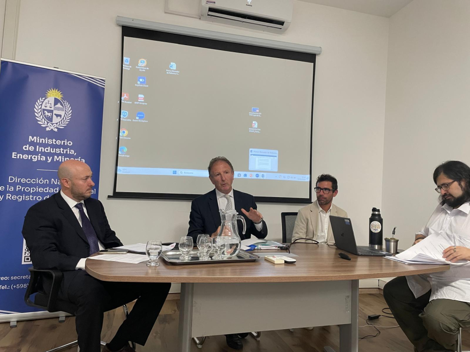 Cuatro personas sentadas detrás de una mesa y con una pantalla al fondo