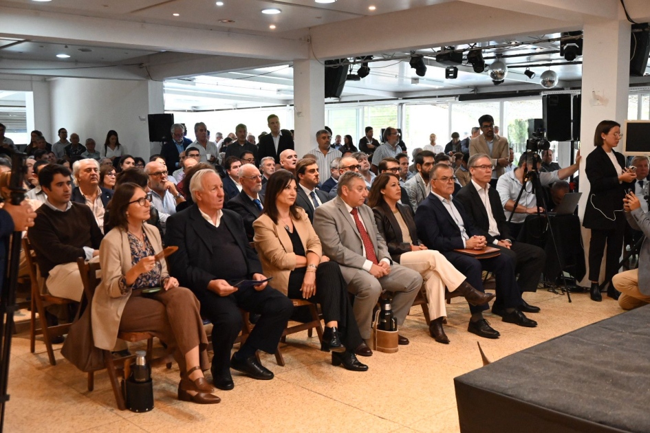 Sala de eventos llena de persoas sentadas, en la primera fila autoridades. 