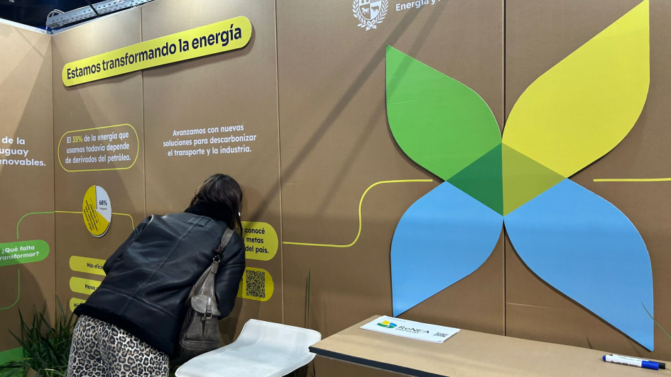 Stand del MIEM Mujer mira por una mirilla en el stand del MIEM