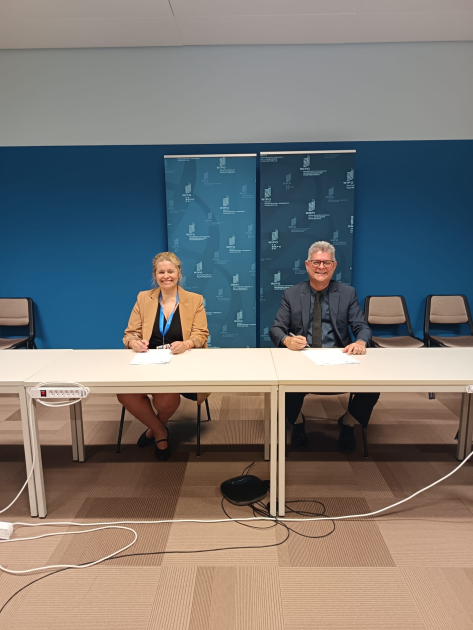 Firma de memorando de entendimiento entre DNPI e INPI de Brasil. Foto: DNPI. Ds personas sentadas detrás de una mesa firman un acuerdo