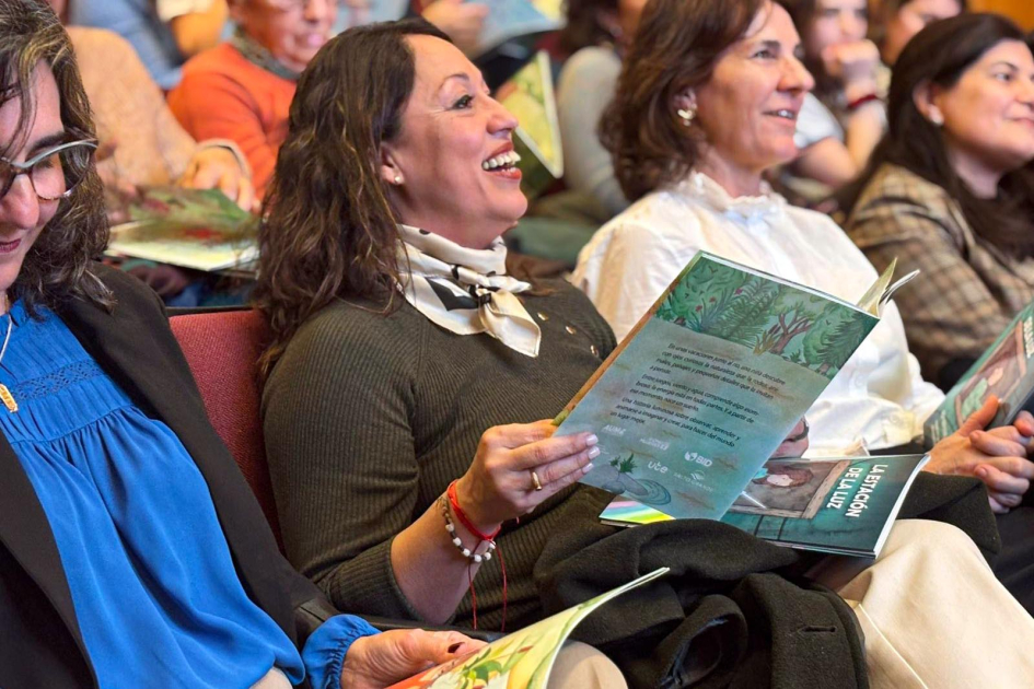 Fernanda Cardona Ministra Cardona sentada entre el público, sostiene un libro en sus manos y sonríe