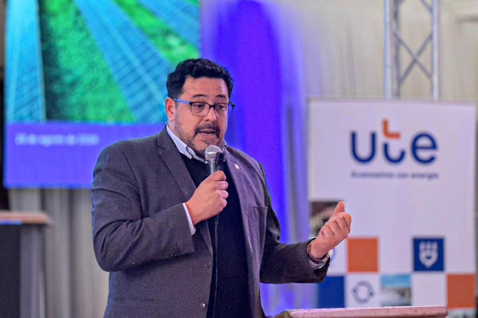 Alejandro Sánchez, secretario de la Presidencia de la República Sánchez habla desde un atril; detrás, banner de UTE