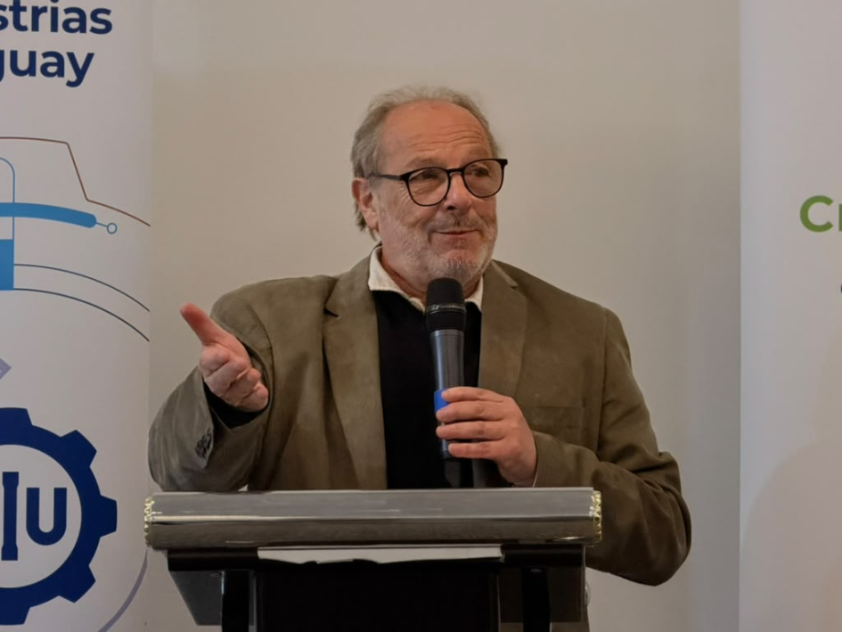 Olesker habla desde un atril; detrás, banner de la CIU