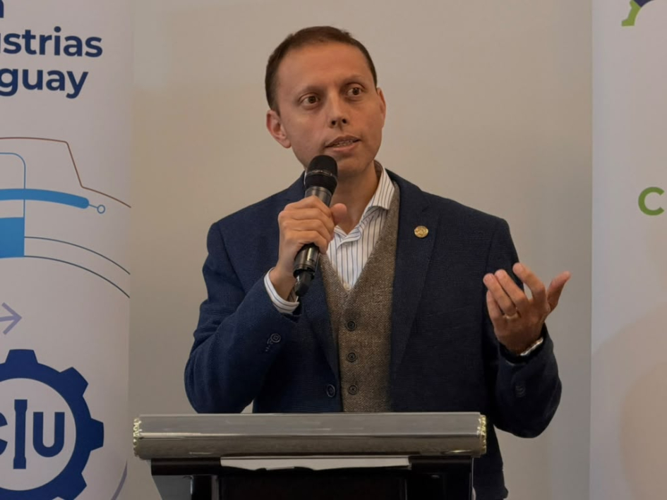 Ilhenferld habla desde un atril; detrás, banner de la CIU