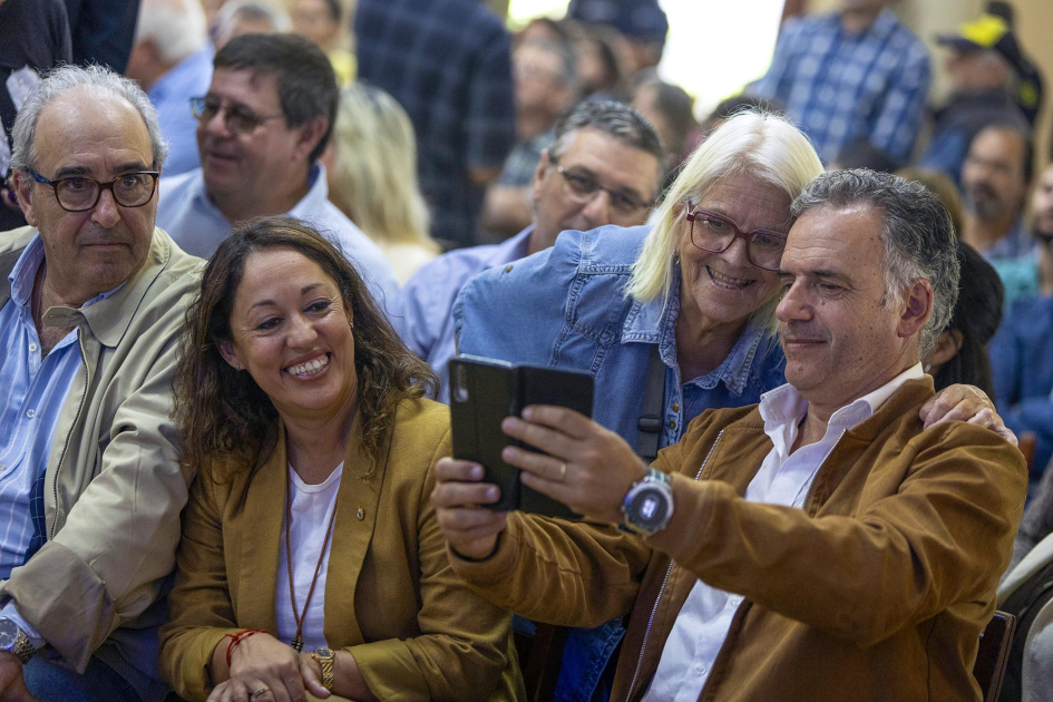 Cardona y Orsi sonríen con otras personas, mientras él se saca una foto con el celular