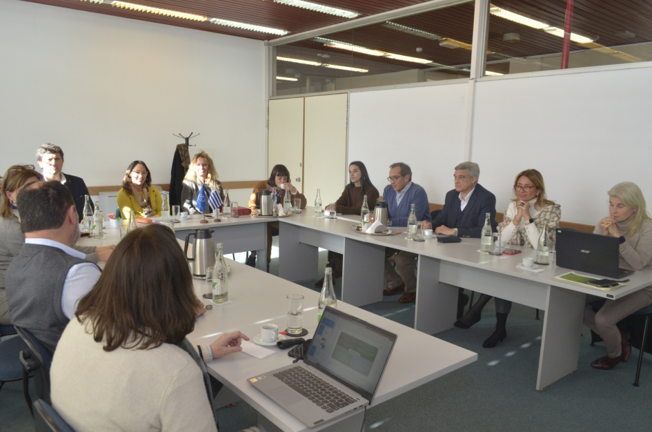 Reunión con el equipo del LATU Grupo de personas sentadas en mesas en forma de "u"