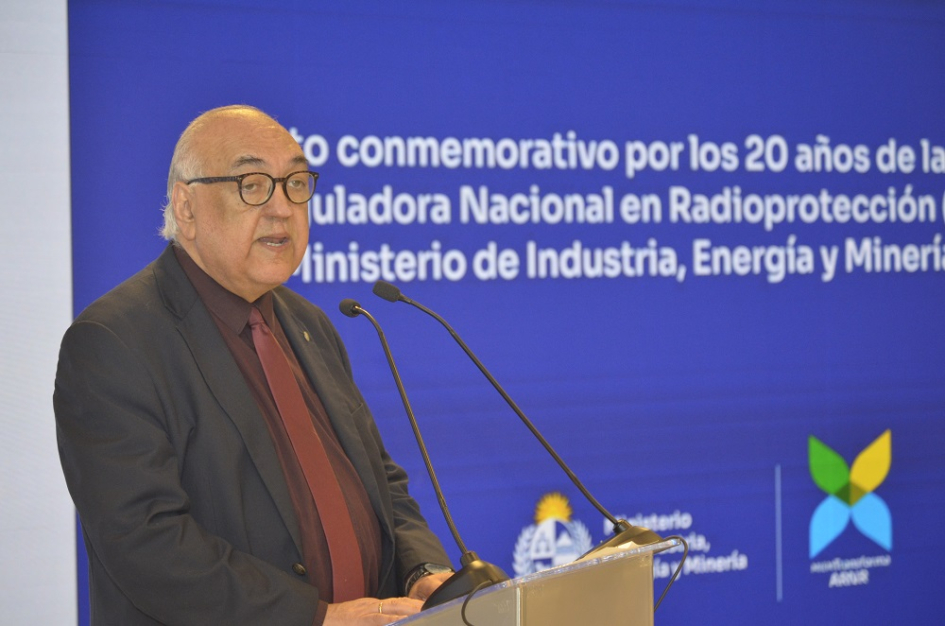 Alejandro Nader Alejandro Nader habla micrófono. Detrás pantalla azul con texto y logos institucionales