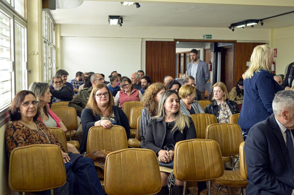 Público de la actividad Funcionarios sonríen en el público de la actividad; a su lado hay ventanales