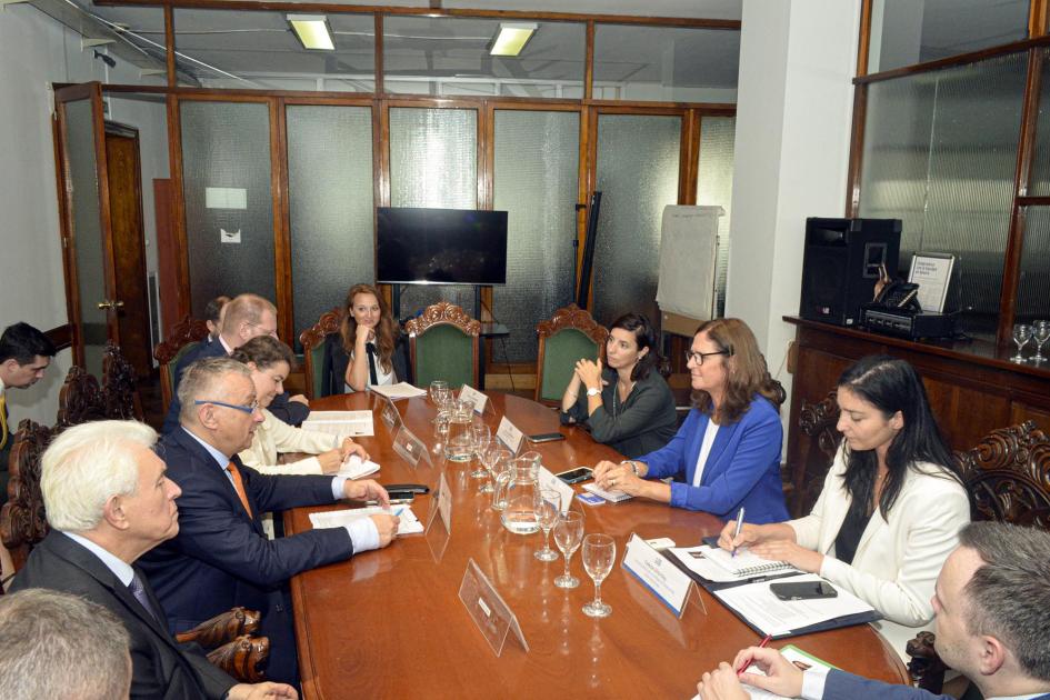 Representantes de ambas delegaciones, reunidos en una mesa de madera, en una habitación vidriada