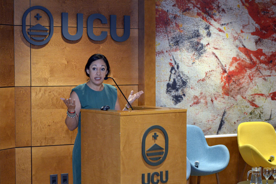 Ministra Cardona haba a micrófono desde un atril que tiene logo de la UCU. 