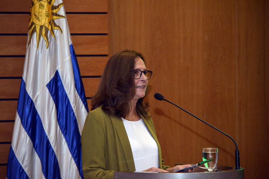 Ministra Facio habla desde un atril; detrás, la bandera uruguaya