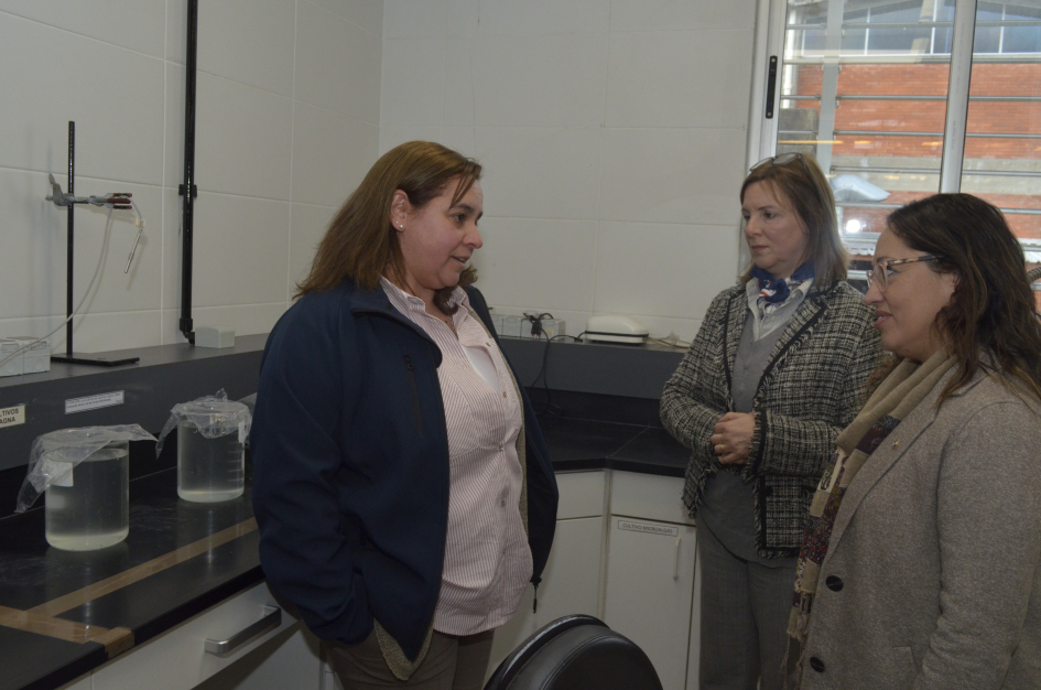 Recorrida por los laboratorios del LATU Ministra Cardona dialoga con una funcionaria de túnica, junto a otra mujer, en un laboratorio