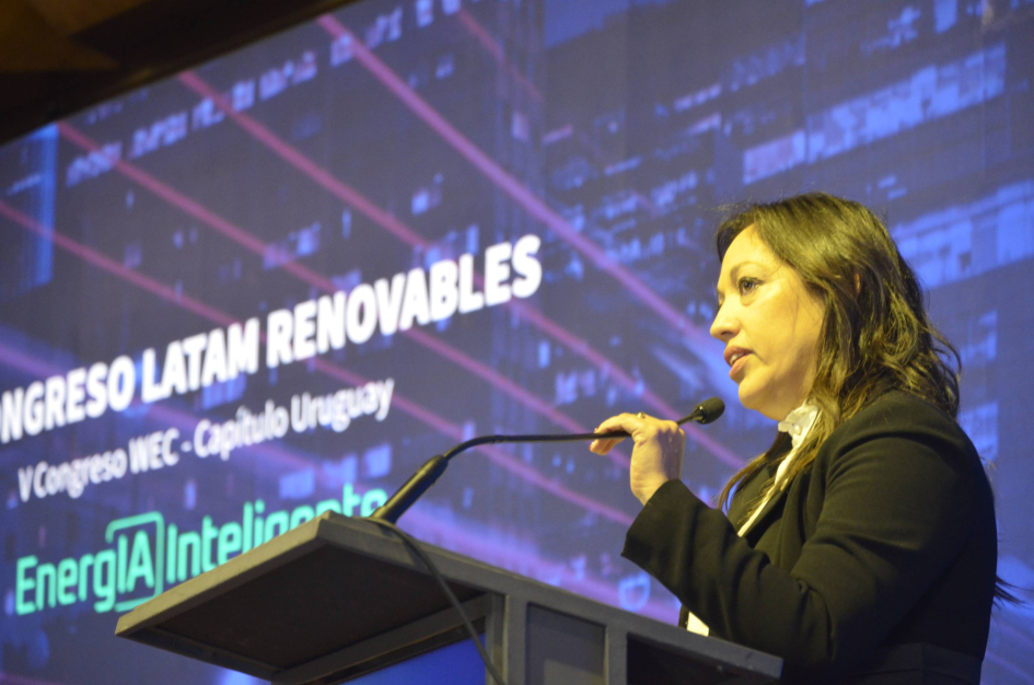 Ministra Fernanda Cardona Ministra Cardona habla desde un atril y sostiene el micrófono; detrás, pantalla del evento