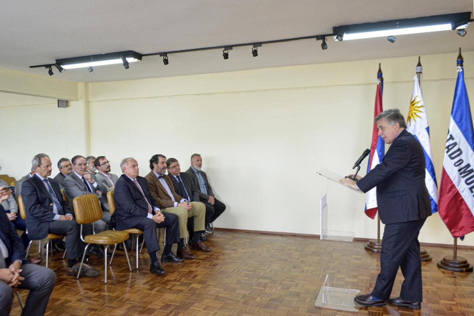 Ministro Paganini habla frente al público; a su lado están los pabellones patrios