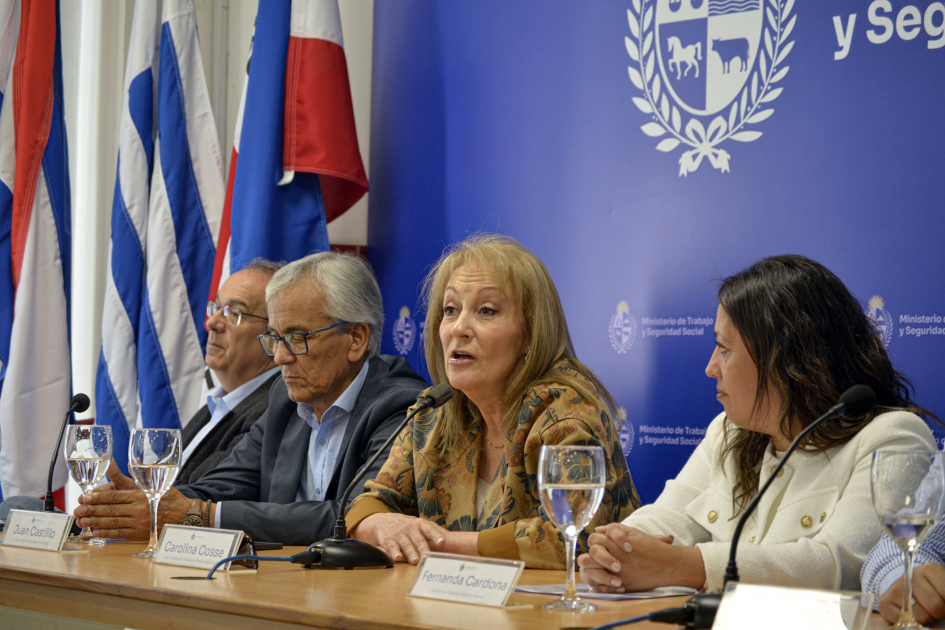 Cosse habla, junto a Cardona, Castillo y Mahía; detrás, banderas y bannera azul