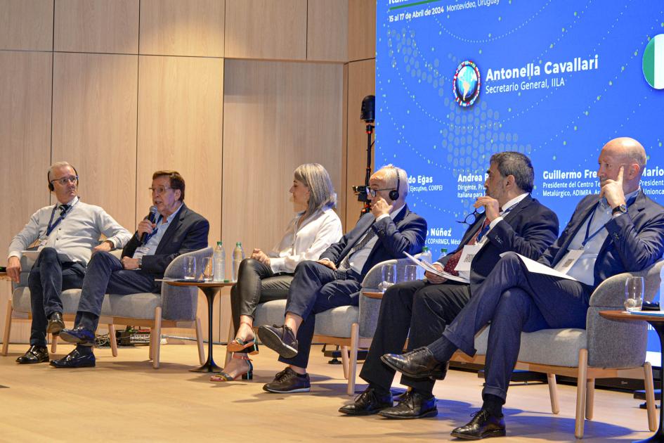 Primera parte del panel de internacionalización de las mipymes Seis hombres están sentados en sillones; detrás, una gran pantalla
