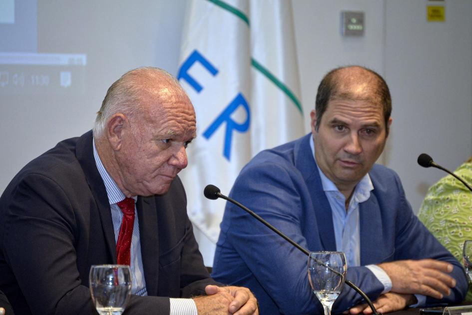 Flavio Caiafa, presidente de la ANII Caiafa habla, sentado, junto a Verri; detrás, bandera del Mercosur