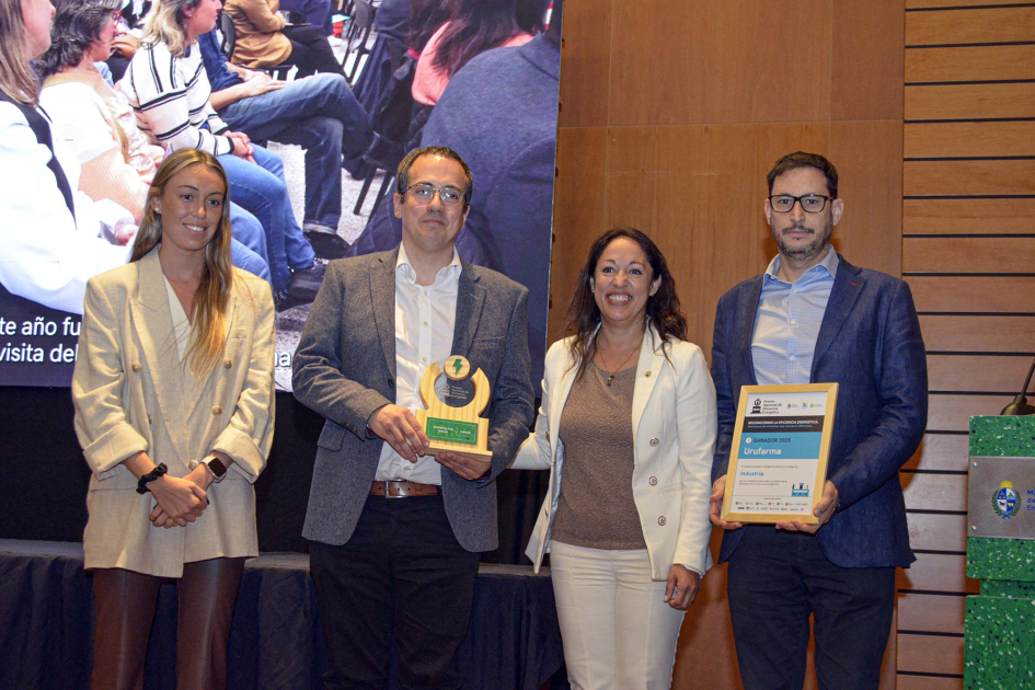 Ministra y tres personas más entregan y reciben el premio; detrás, pantalla