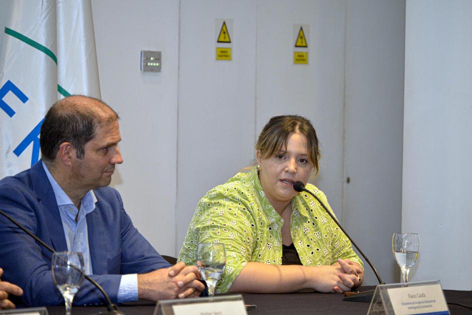 María Pía Alonso, quien expuso en representación de ONUDI Cono Sur María Pía Alonso habla, sentada, junto a Caiafa; detrás, bandera del Mercosur