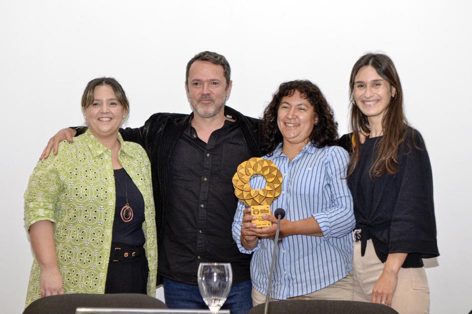 Segundo premio de la categoría Mipymes: Pintura SUMA Una mujer sostiene un premio, junto a una mujer, un hombre y la representante de ONUDI