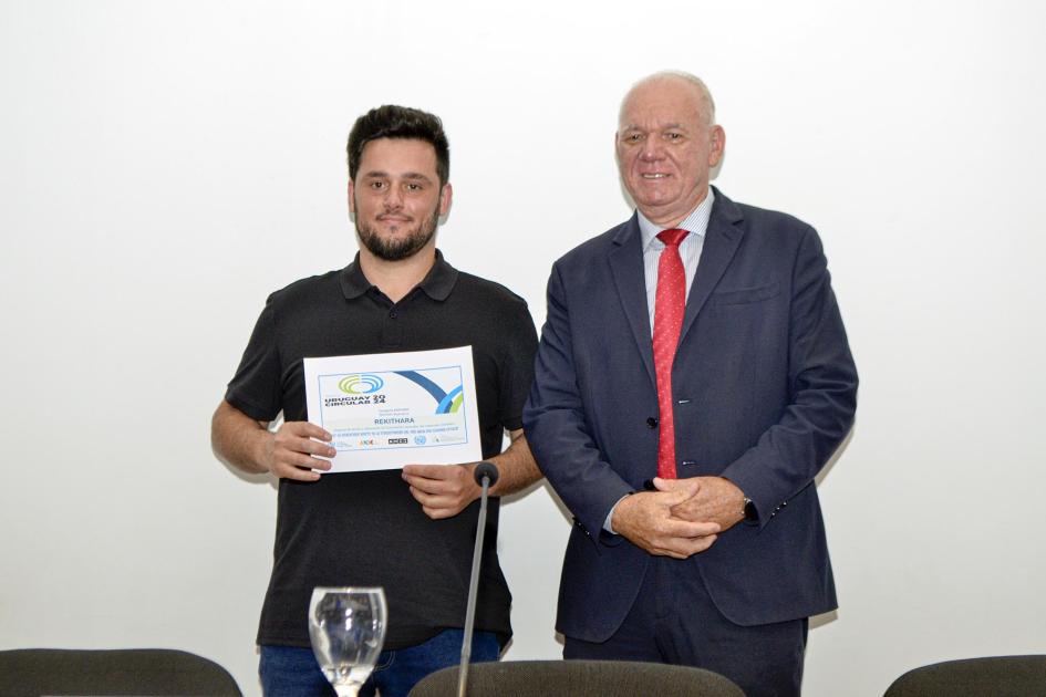 Mención especial de la categoría Mipymes: Rekithara Verri, de pie, junto a un hombre que sostiene un diploma